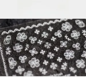 Macro detail of white lace flower and bow nail stickers on clear film for nail art