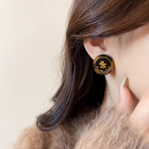 Gros plan de boucles d'oreilles rétro en résine écaille avec cheval à bascule doré