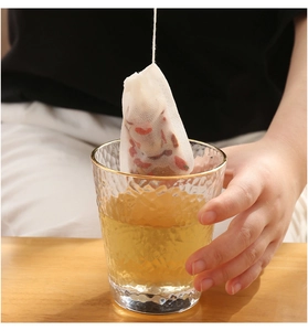 Detailansicht eines Vlies-Teebeutels zum Filtern von Kräutertee in einem Glasbecher