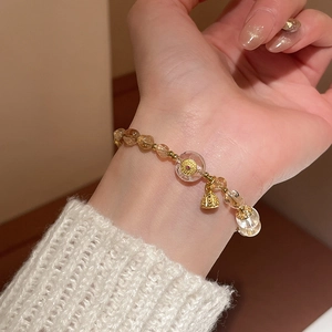 Detailed view of beaded crystal bracelet with golden lotus seed pod and bell pendant