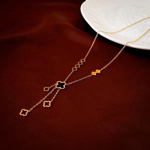 Détail d'un collier trèfle avec incrustation noire et breloques dorées sur tissu
