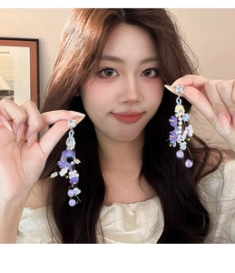 Close-up of long tassel earrings with purple fabric flowers and iridescent beads on model
