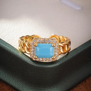 Macro shot of gold ring with sky blue rectangle zircon and side diamonds on leather box