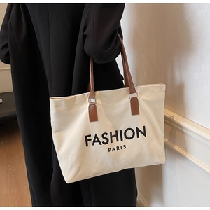 Detail der großen Canvas-Tragetasche mit braunen Ledergriffen und Fashion Paris Aufdruck
