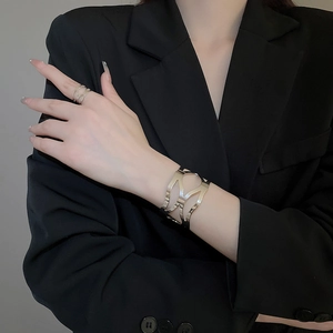 Close-up of polished silver hollow cuff bracelet and ring set on black fabric background
