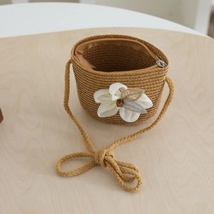 Detail of woven straw crossbody bag for girls with decorative silk flower and wooden bead