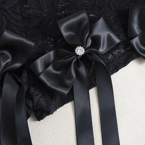 Détail de dentelle noire avec un nœud en satin et une pièce centrale en strass étincelants