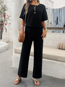 Detailed view of the black knit short sleeve top and wide-leg trousers on a summer vacation