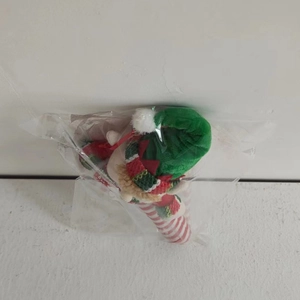 Detailed view of a Christmas elf plush toy in red and green striped outfit inside packaging
