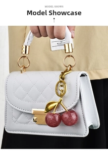 Close-up of red glitter cherry charm attached to a white quilted PU leather handbag
