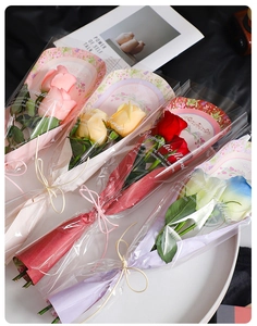 Close-up of four colorful soap rose bouquets in transparent bags with Romantic Floral text