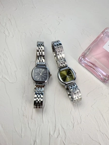 Detail view of square women watches with green and black dials on silver steel strap