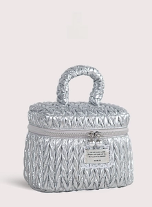 Detail view of silver quilted makeup bag with woven handle and pearl zipper charms