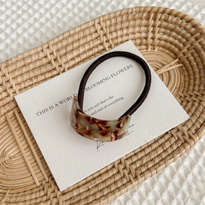 Macro detail of tortoiseshell acetate hair tie with handmade gold lettering on tray