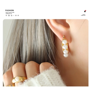 Detailed view of elegant gold-plated bean pod earrings and ring with faux pearls