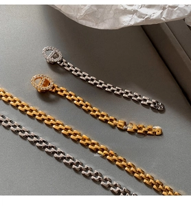 Detail of gold and silver chain bracelets with sparkling diamond-encrusted anchor links
