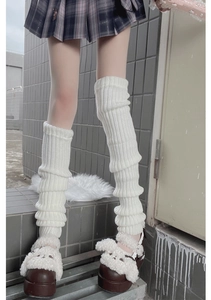 Close-up of knit cream leg warmers with vertical ribbed texture and layered slouchy style