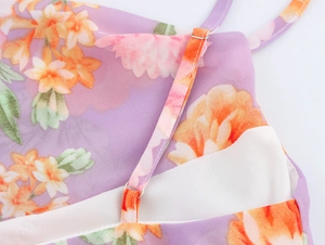Detail of adjustable thin strap and orange floral pattern on purple sleeveless long dress