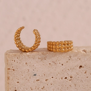 Détail de boucles d'oreilles dorées à triple rangée de perles sur support minéral