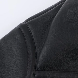 Detailed macro view showing black faux leather texture and precise stitching on the jacket