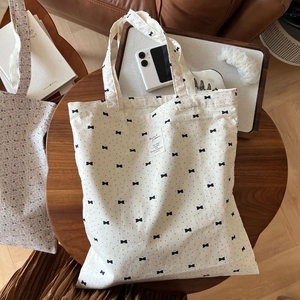 Detail of grey-black floral bow cotton shoulder bag with printed label on thick canvas