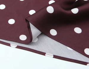 Detail of red and white polka dot fabric texture with visible twill weave and stitching
