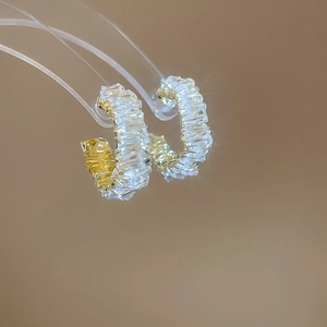 Macro view of C-shaped earrings featuring baguette-cut crystals and gold wire wrapping