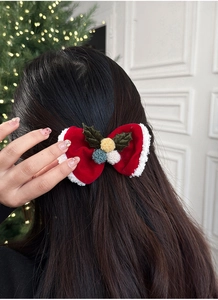 Gros plan d'une pince à cheveux de Noël avec nœud rouge et détails de houx festifs