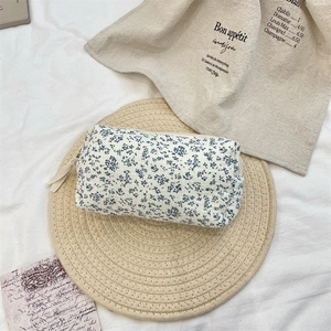 Blue floral cosmetic bag with cotton texture on woven mat with vintage aesthetic