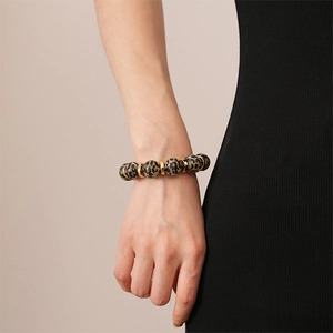 Detail of leopard print acrylic beads and gold spacers on a stretchy bracelet worn by model