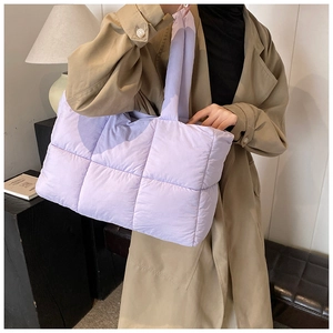 Quilted lavender puffer tote bag shown with camel trench coat in a cozy interior setting