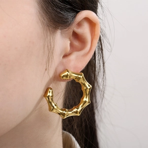 Close-up of a model wearing a gold hollow bamboo C-shaped earring in stainless steel