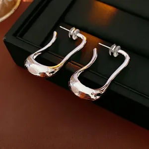 Minimalist irregular U-shaped silver earrings on black leather jewelry display box