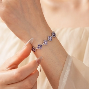 Macro shot of silver clover bracelet with purple stones on a model's wrist