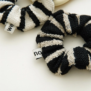 Detailed view of two black and white striped tweed scrunchies with knitted texture