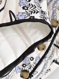 Detail of floral printed quilted jacket with tortoiseshell buttons and black piping