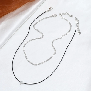 Detail of double-layer necklace with silver heart pendant and black leather cord