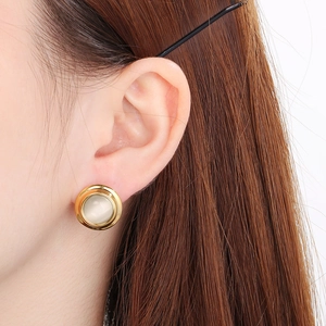 Macro shot of gold-edged pearl stud earrings worn by a model to show elegant fit