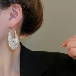 U-förmige Netzohrringe mit großer Perle, getragen von einem Model im schwarzen Blazer