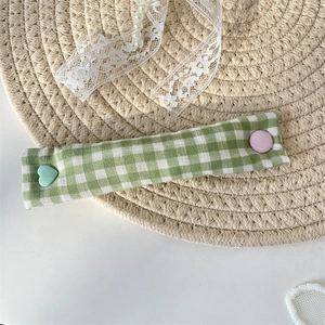 Detail of green checkered fabric cable organizer with colorful heart-shaped snap buttons