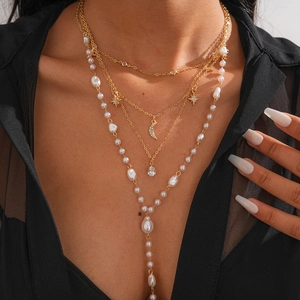 Detail of layered gold necklace with imitation pearls, star and moon diamond pendants