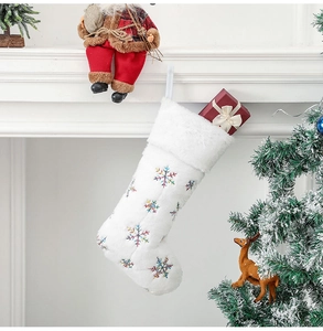 Détail de chaussette de Noël en peluche blanche avec broderie flocon à paillettes