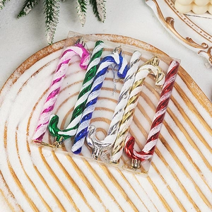 Set of 6 colorful candy cane Christmas ornaments with glitter stripes on snowy wood