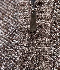 Close-up of the metal zipper and thick cable knit texture on a coffee-white sweater