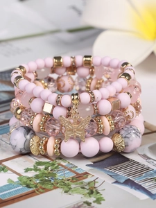 Detail eines mehrlagigen Boho-Armband-Sets mit rosa Perlen und goldenem Schmetterlingsanhänger