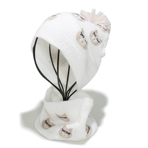 Close-up of white knitted baby hat and scarf set featuring cute cat motifs and pink pom-pom