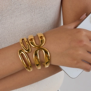 Close-up of golden wide open bangle with geometric U-shaped sculptural design on wrist