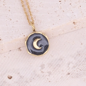 Close-up of gold moon and stars pendant with dark grey inlay on stainless steel chain