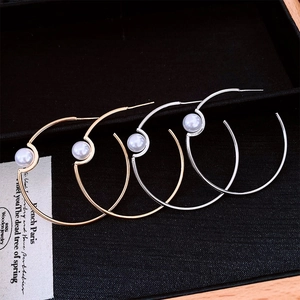 Detailed view of gold and silver hoop earrings with white pearls in a black jewelry box