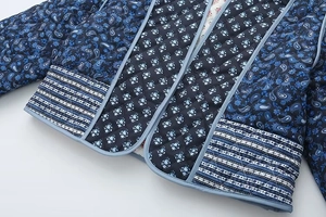 Detail of blue quilted jacket featuring paisley floral patterns and precise piping finish